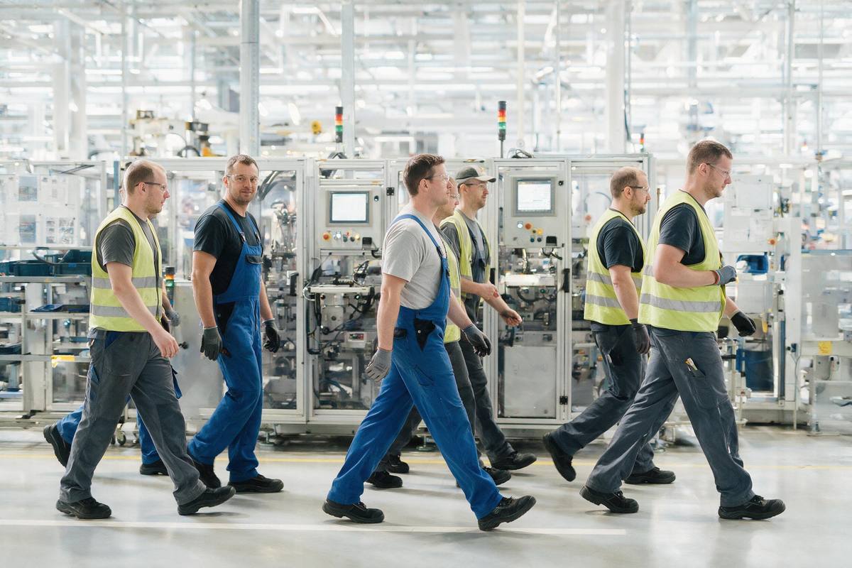 Automotive line workers in a bright modern Slovak plant walking past machinery