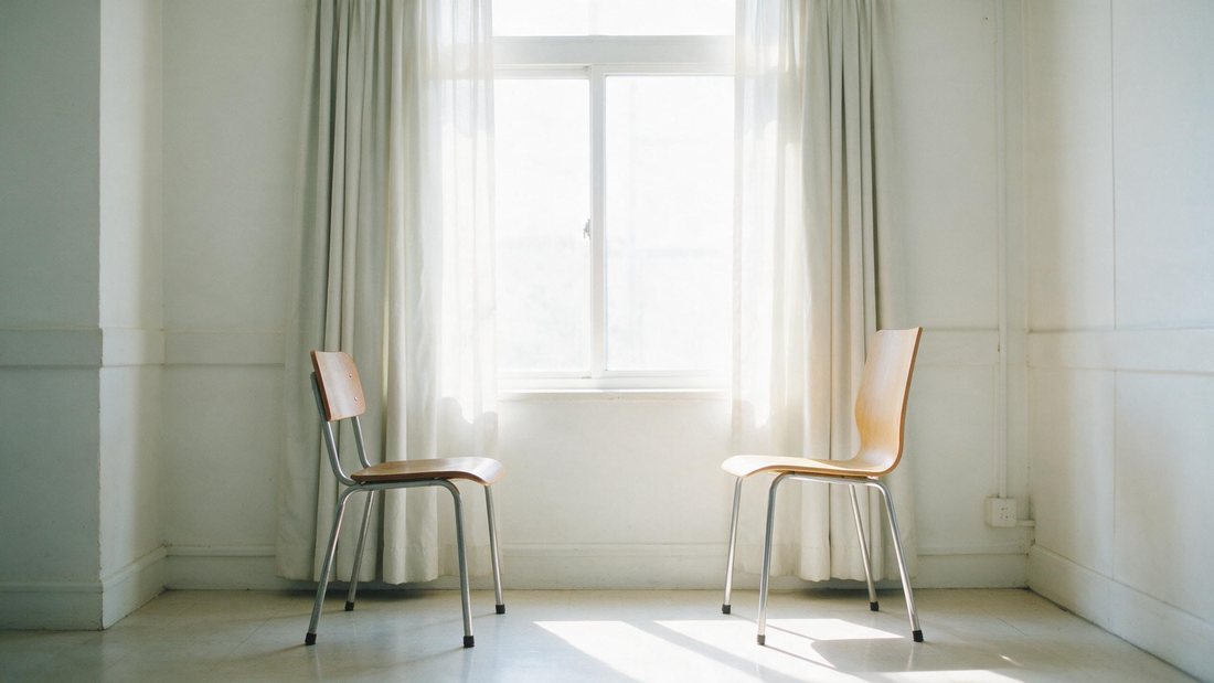 Two chairs facing each other by a bright quiet window